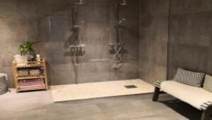A modern bathroom with a shower, a small shelf with a plant, and a bench. - Solferie Justnesskauen 21 (Kristiansand)