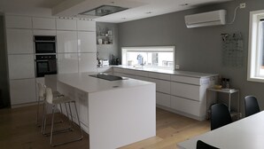 A modern kitchen with white cabinetry, a central island, and a built-in oven. - Solferie Justnesskauen 21 (Kristiansand)