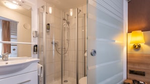 A modern bathroom with a glass-enclosed shower, a sink with a mirror, and a toilet. - Trip Inn City Hotel Hamm Koblenz (Koblenz)