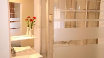 Un baño con ducha, lavabo y espejo.