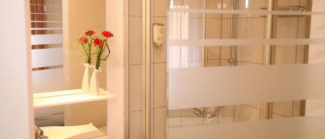 Un bagno con doccia, lavandino e specchio.
