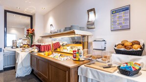 A buffet setup with various food items, a coffee station, and a wall-mounted information board. - Trip Inn City Hotel Hamm Koblenz (Koblenz)