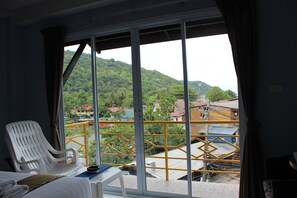 A room with a balcony, a white plastic chair, a small table, and a bed. - Nap Inn (Ko Pha-ngan)