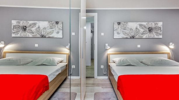 A mirrored room with two beds, grey walls, and floral artwork. - Fiorello Apartment (Rijeka)