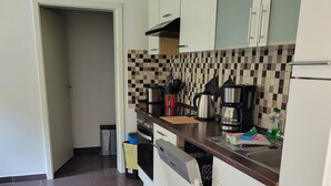 A kitchen with a tiled backsplash, a dishwasher, a coffee maker, and a trash bin. - Apartment "Dat Nüst", terrace, garden, mod. bath (Manslagt)