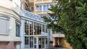 A hotel entrance with a glass facade, a visible reception area, and a potted plant outside. - TRIP INN Hotel Aschaffenburger Hof (Aschaffenburg)