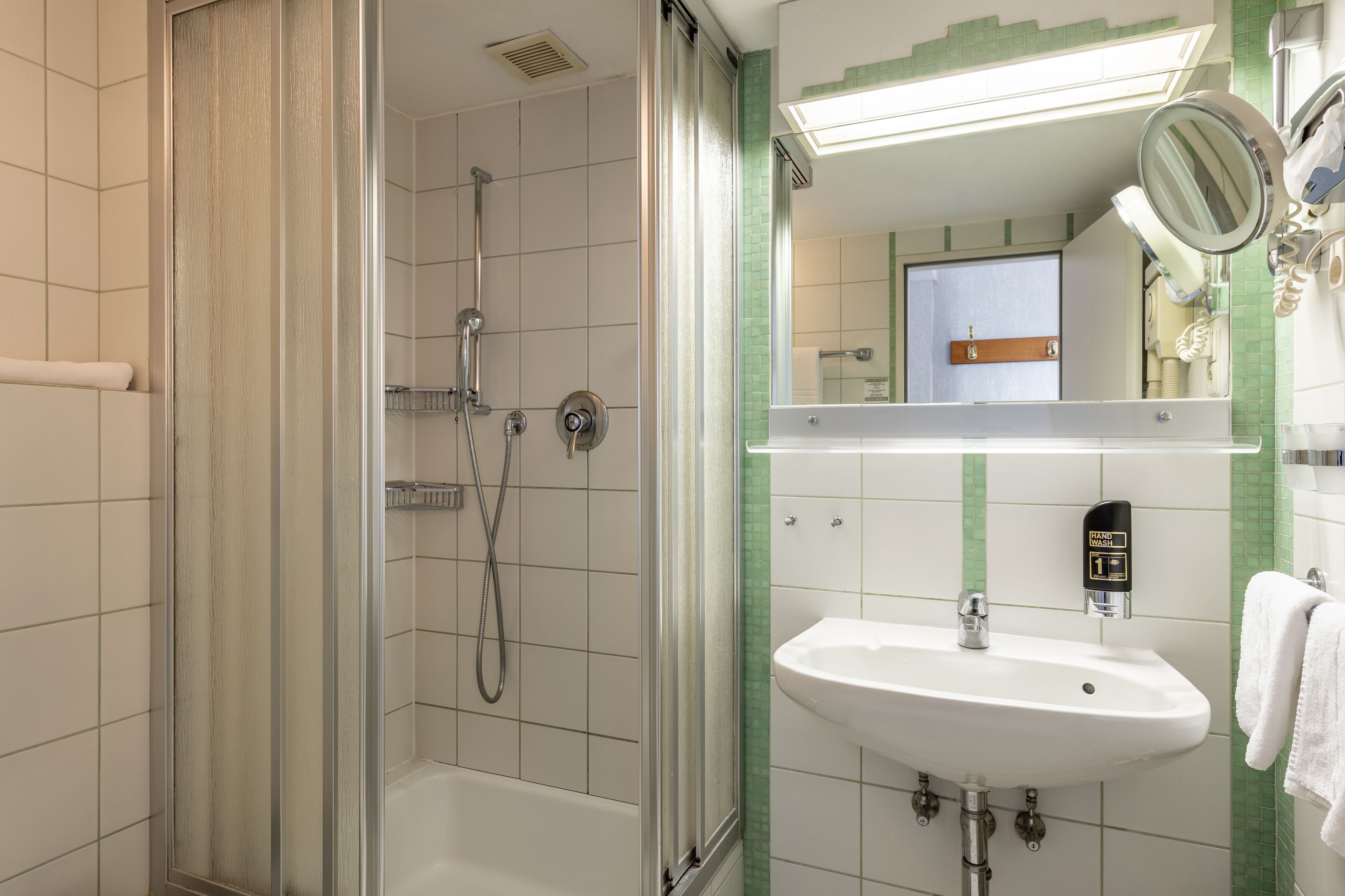 A bathroom with a shower, sink, and mirror.