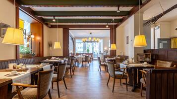 Ein Restaurant mit Holztischen und -stühlen, einer Chandelüster und Blick auf die Straße.