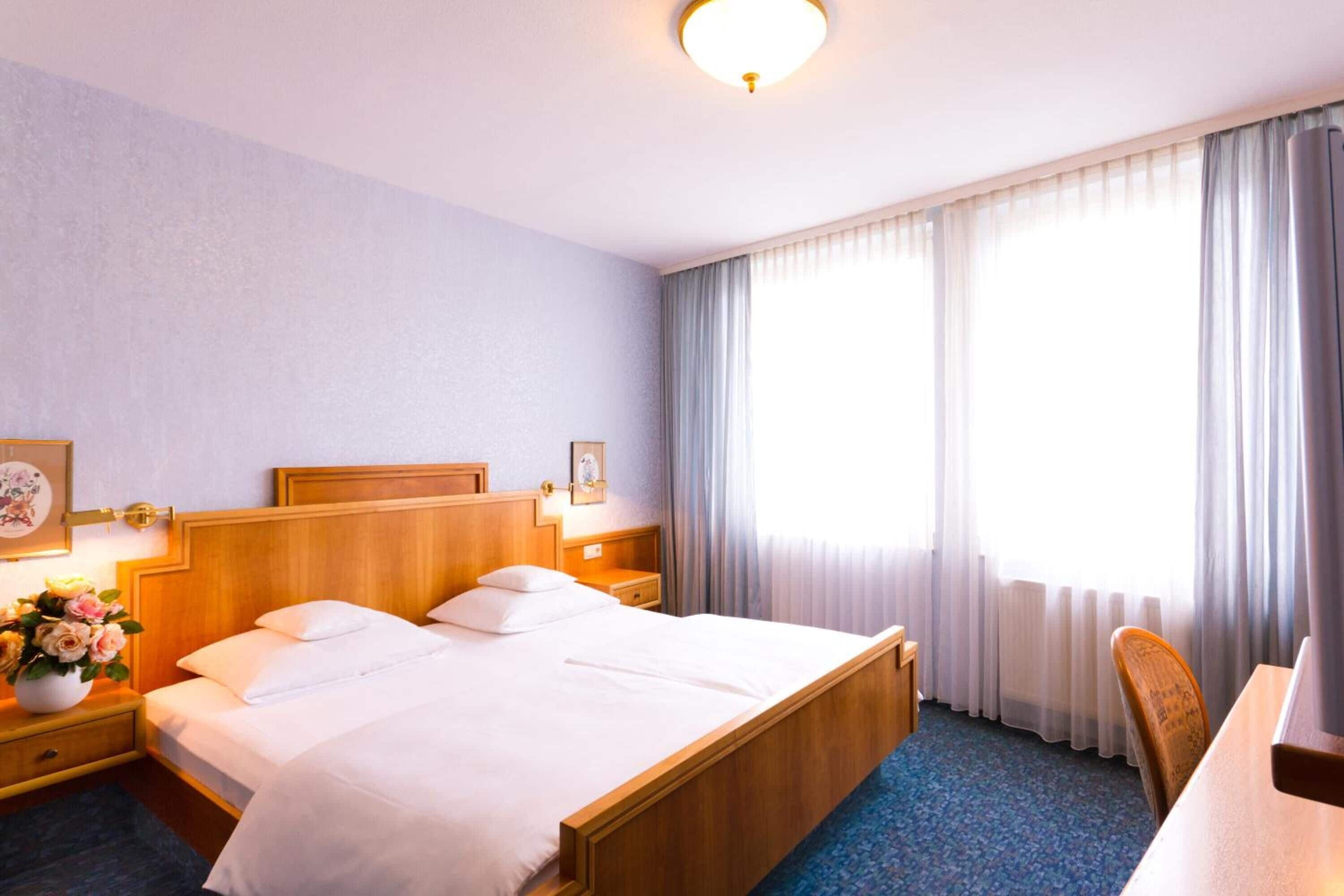 A hotel room with a double bed, bedside tables, a desk, and a chair.