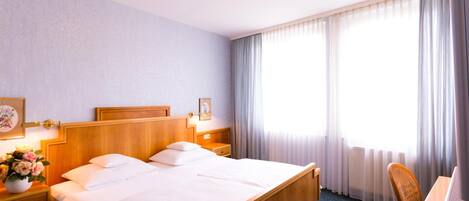 A hotel room with a double bed, bedside tables, a desk, and a chair.