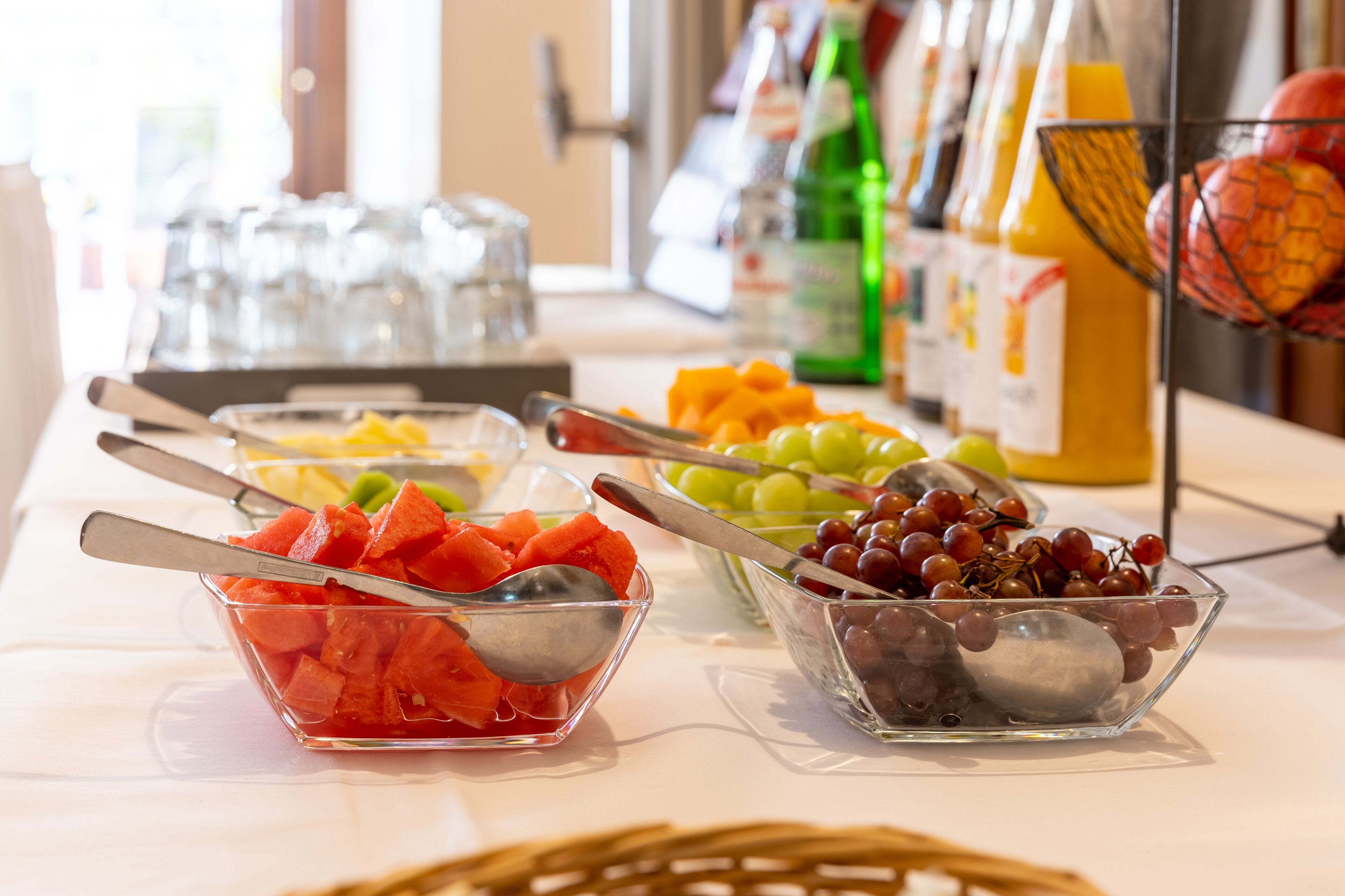 A buffet table with various fruits and beverages.