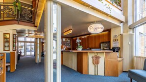 A reception area with a counter, wooden cabinets, a clock, and a sign that reads "Reception". - TRIP INN Hotel Aschaffenburger Hof (Aschaffenburg)