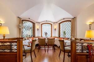 Un comedor con techo alto, ventanas arqueadas y mobiliario de madera.