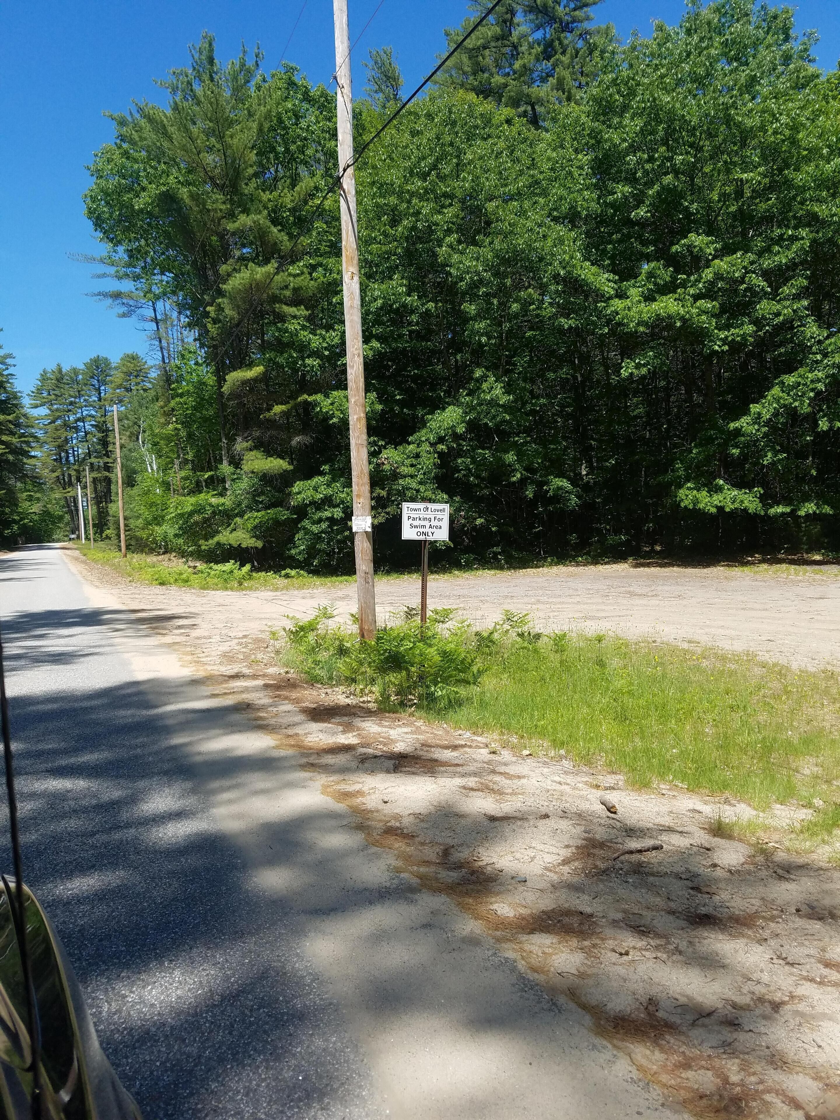 A road with a sign indicating parking is for the Town of Lovell's swim area only.