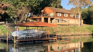 A lakeside house with a dock and a covered boat area.