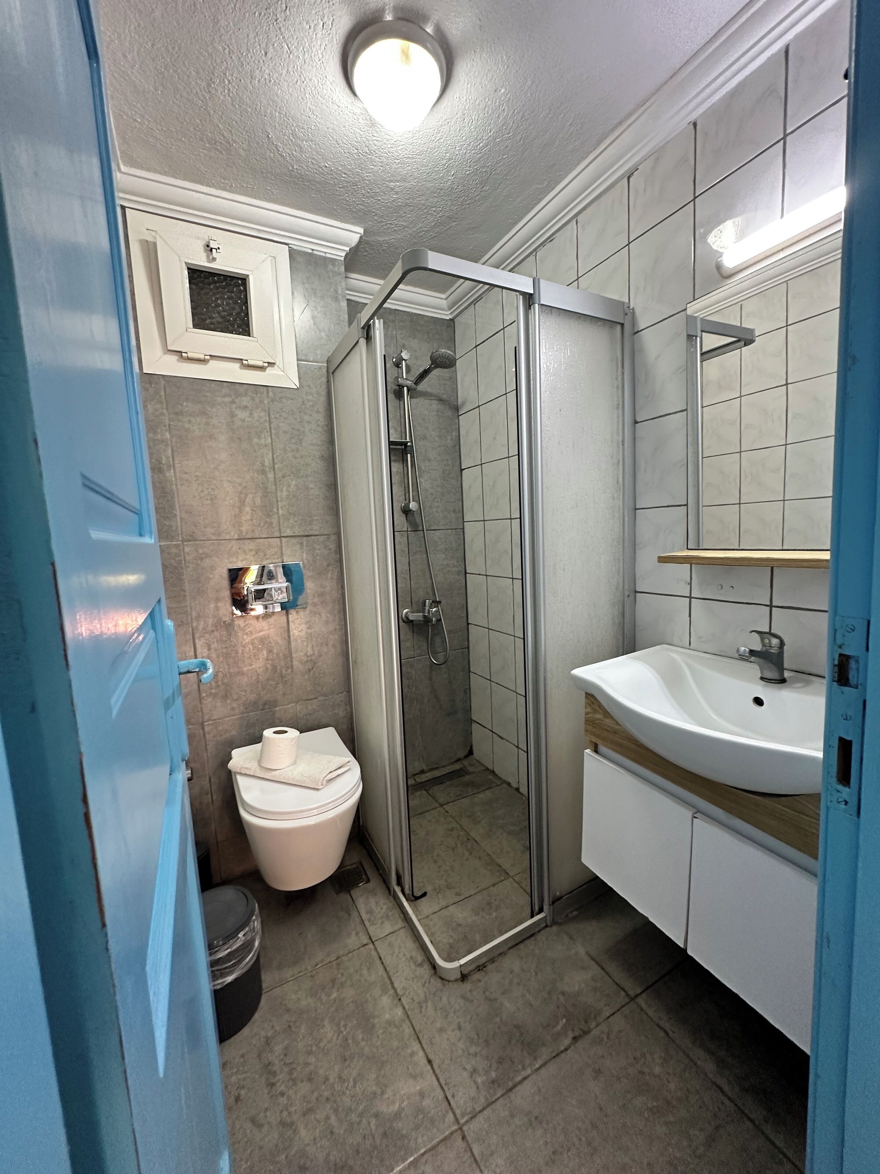 A bathroom with a shower, toilet, sink, and a mirror.