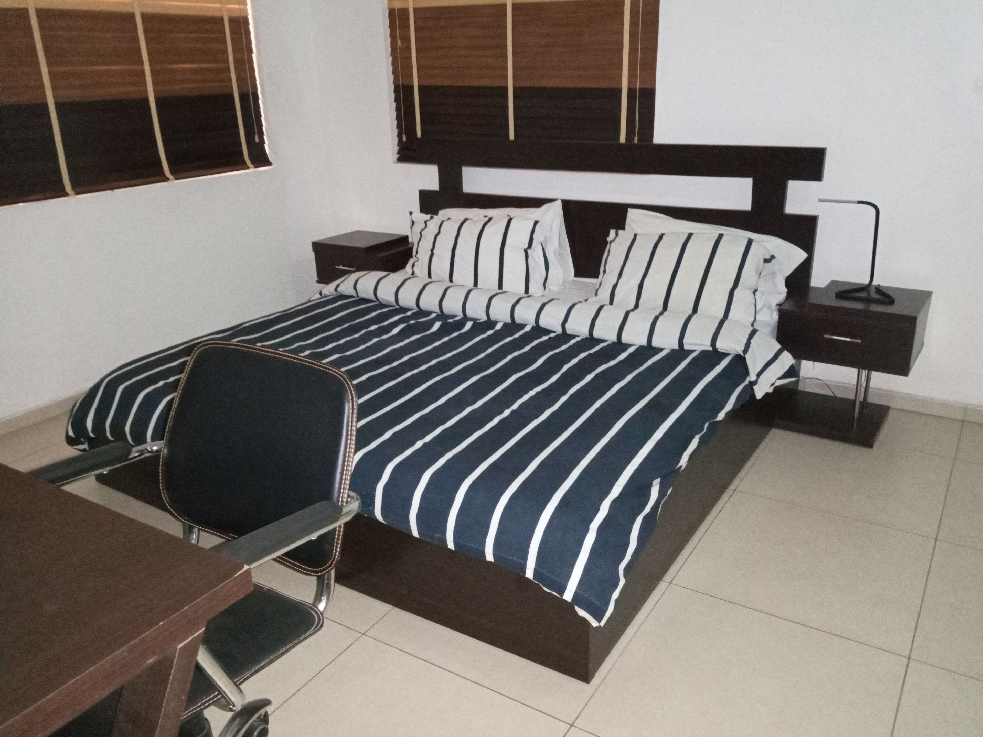 A bedroom with a bed, bedside tables, a chair, and a desk.