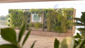 Een bordje voor Hotel Muchiutt Park, met een bakstenen muur en groene planten.