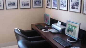 Une pièce comprenant un bureau, deux chaises, un ordinateur, une imprimante et des tableaux encadrés accrochés au mur.