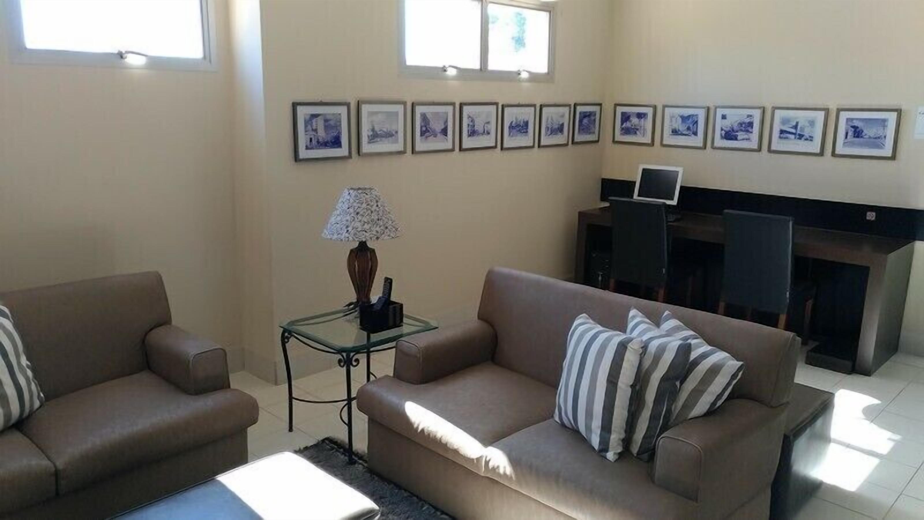 A living room with two sofas, a coffee table, a lamp, and a fireplace. There are framed pictures on the wall.
