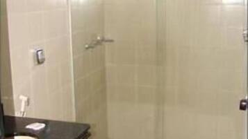 A bathroom with a toilet, a sink, and a glass-enclosed shower area.