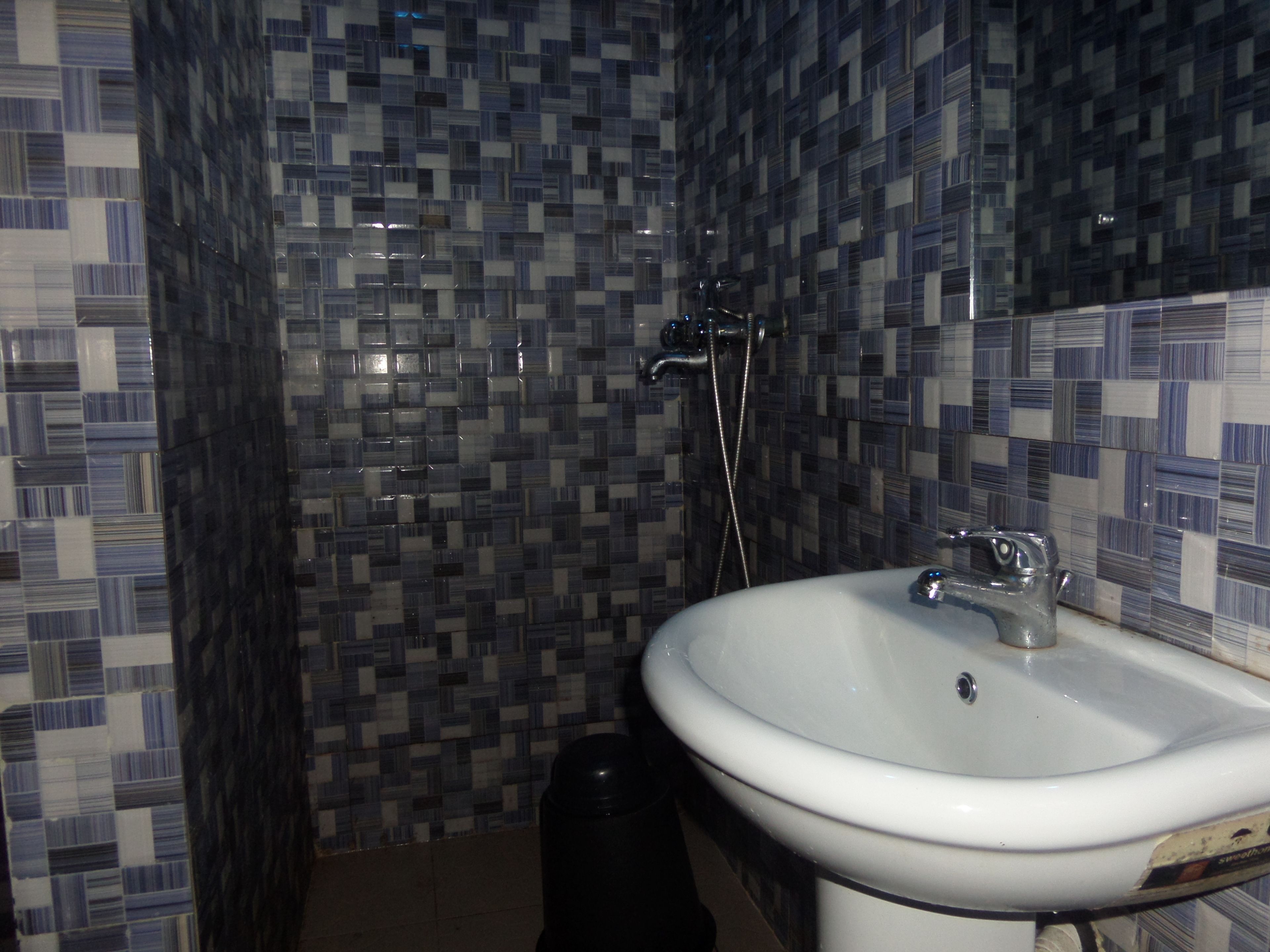Un baño con lavamanos blanco, espejo y paredes con azulejos.