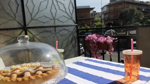 A table with a clear glass pie on a blue and white striped tablecloth, a glass with a straw, and a chair with pink flowers.