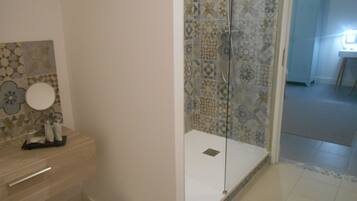 Un baño con ducha, inodoro y lavamanos con espejo.