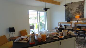 A breakfast bar with a clear glass display case, a coffee station, and a view of the outdoors.