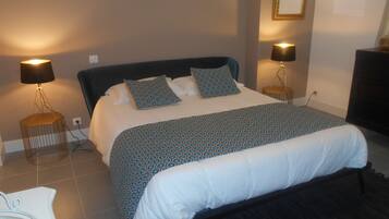 A neatly made bed with patterned bedding, two bedside lamps, and a bedside table with a lamp.