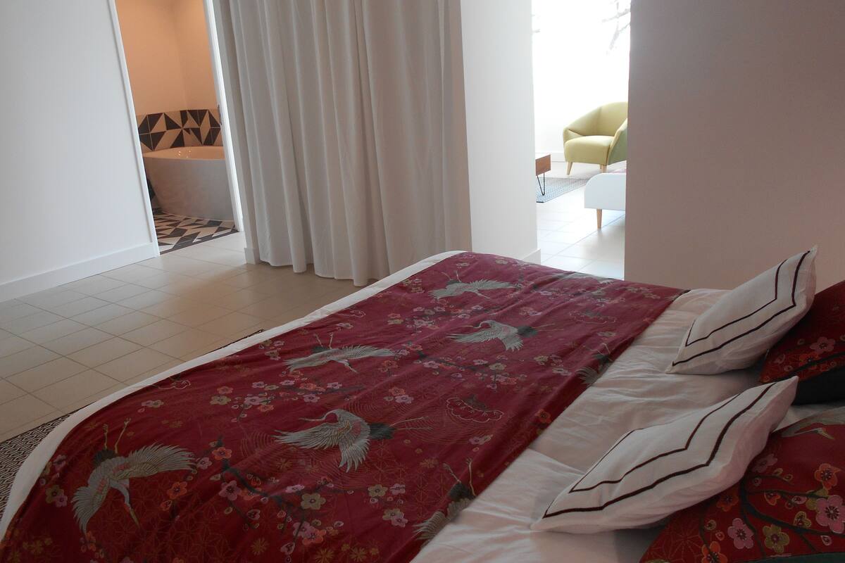 Ein Schlafzimmer mit Bett, Stuhl und Blick auf einen Balkon.
