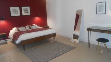 Un dormitorio moderno con cama, mesitas de noche, escritorio y espejo.