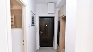 A narrow hallway with a dark wooden door, a white wall, and a tiled floor. - Apartment Fran Green & Blue (Rijeka)