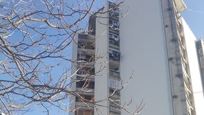 A tall residential building with multiple balconies and a parking area in front. - Apartment Fran Green & Blue (Rijeka)