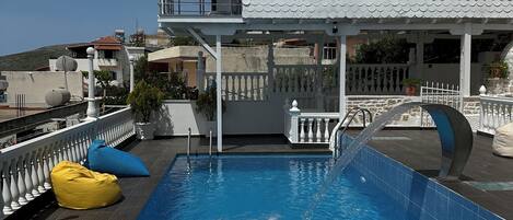 Una piscina en la azotea, con un edificio blanco al fondo.