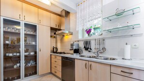 Una cocina moderna con armarios de madera, lavavajillas, estufa y ventana con cortinas de encaje.