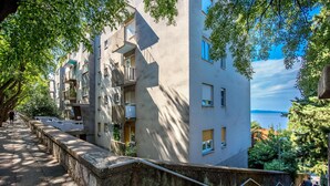 Un edificio de varios pisos con balcones, una escalera de piedra y vista al mar.