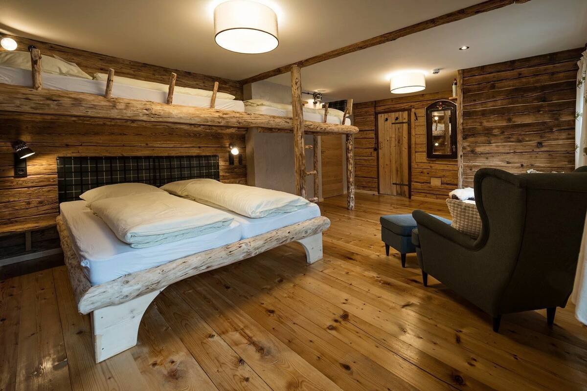 Um quarto rústico de madeira com uma cama, uma cadeira e parede de madeira.