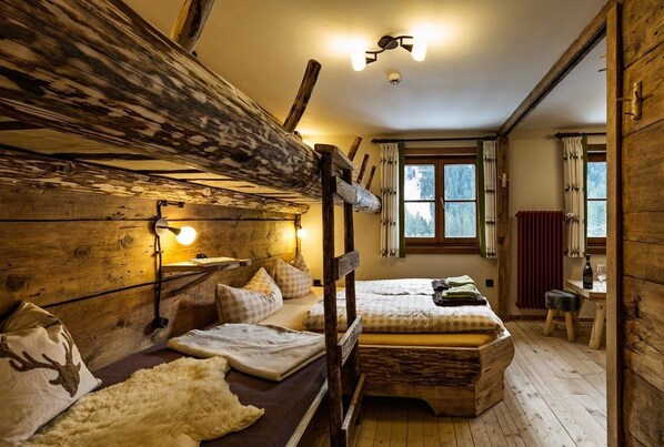 Una habitación rústica tipo cabaña con una litera, un escritorio y una ventana con cortinas.
