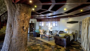 Un'ampia zona giorno con un grande tronco d'albero, un pavimento a scacchi e un soffitto alto con travi in legno.