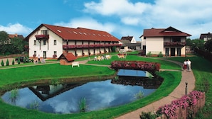 A traditional European-style hotel with multiple guest rooms, a central courtyard with a pond, and a well-maintained garden. - Landgasthof & Hotel Waldow (Guben)