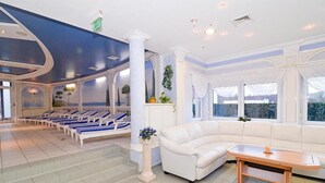 A hotel lobby with a white sofa, a wooden table, and a row of blue and white lounge chairs. - Landgasthof & Hotel Waldow (Guben)