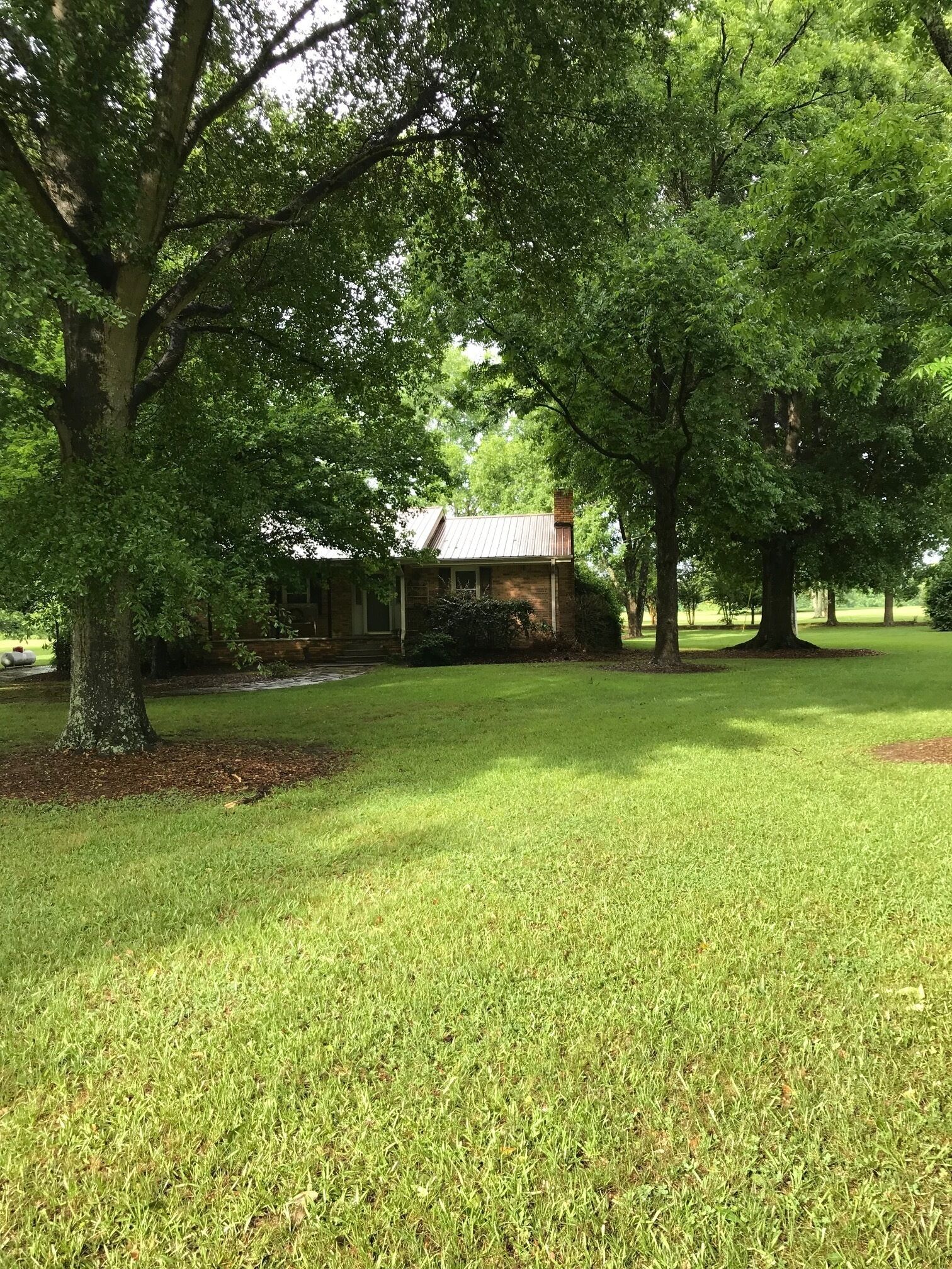 A house surrounded by a well-maintained lawn and large trees.