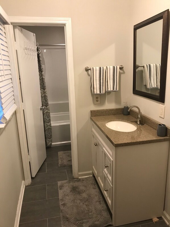 A bathroom with a shower, a sink, and a mirror.