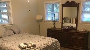 Un dormitorio con cama, cómoda y ventilador de techo.