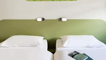 A hotel room with two beds, white bedding, a green headboard, and a wall-mounted light fixture.