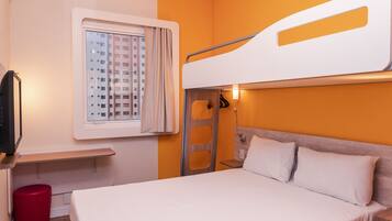 A bunk bed with a window, a red stool, and a TV.