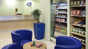 Een receptiezone met een balie, een potplant, zitplaatsen en een presentatie van snacks.