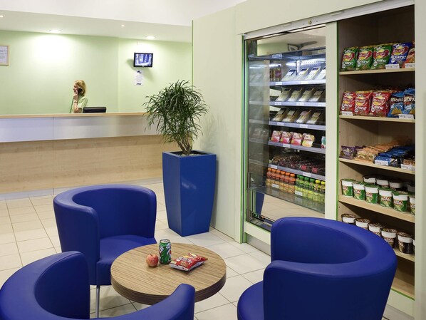 Een receptiezone met een balie, een potplant, zitplaatsen en een presentatie van snacks.