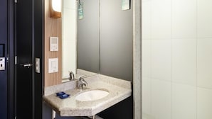 Ein modernes Badezimmer mit einem Granittisch, einem Spiegel, einem Handtuchhalter und einem an der Wand montierten Thermostat.